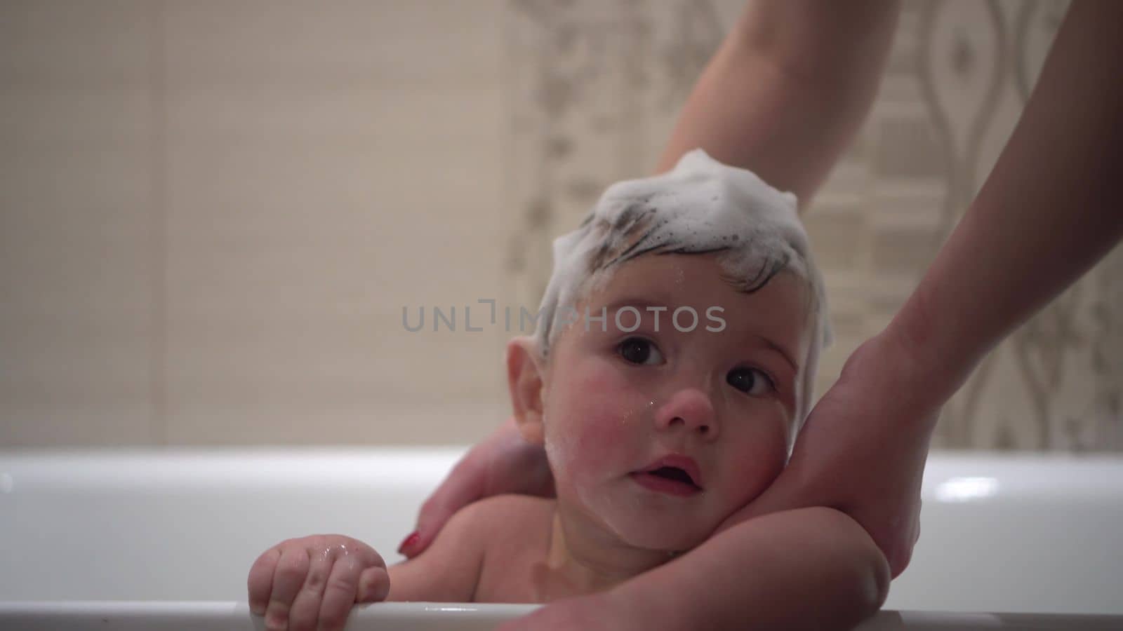 Close-up of a child's face in the bathroom. A little boy in the bathroom bathes with foam on his head. 4k