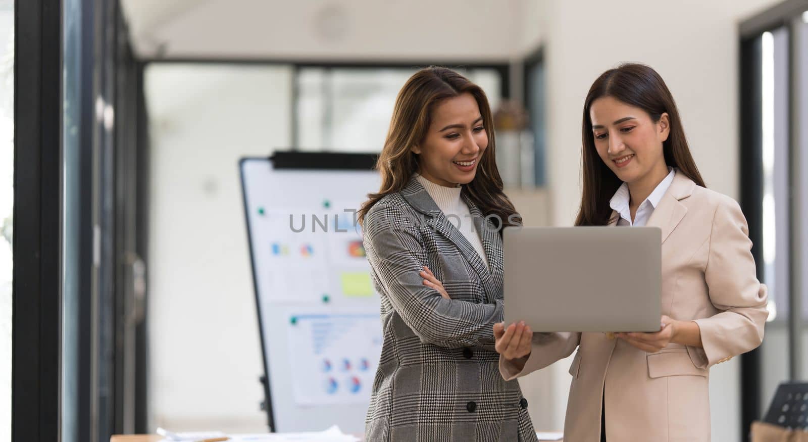 Atmosphere in the office of a startup company, two female employees are discussing, brainstorming ideas to working on summaries and marketing plans to increase sales and prepare reports to managers...