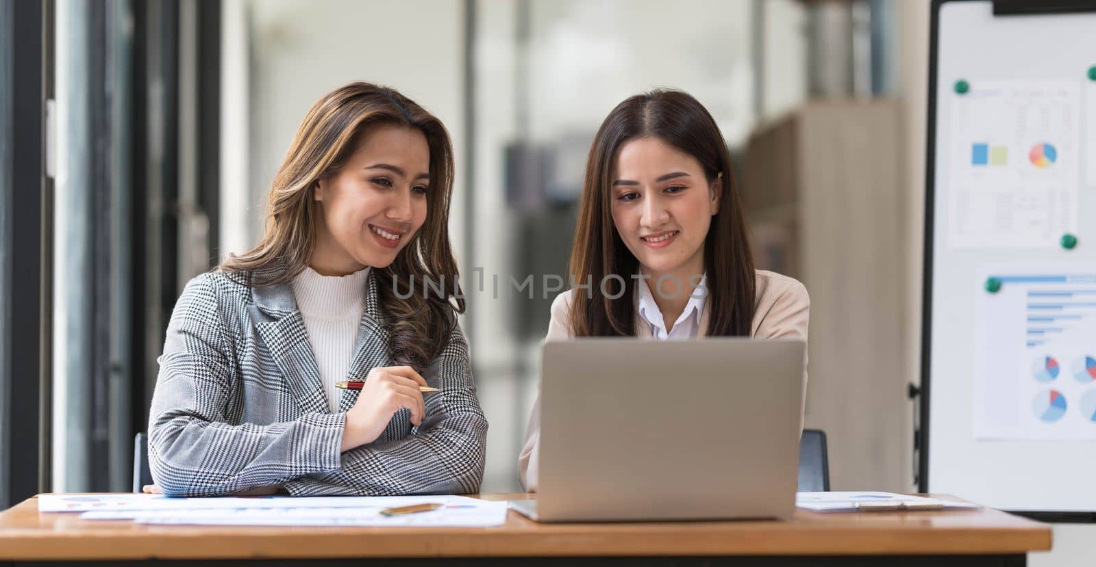 Two young Asian businesswoman discuss financial management planning. new startup project ideas analysis of financial planning and statistics and the investment market at the office by wichayada