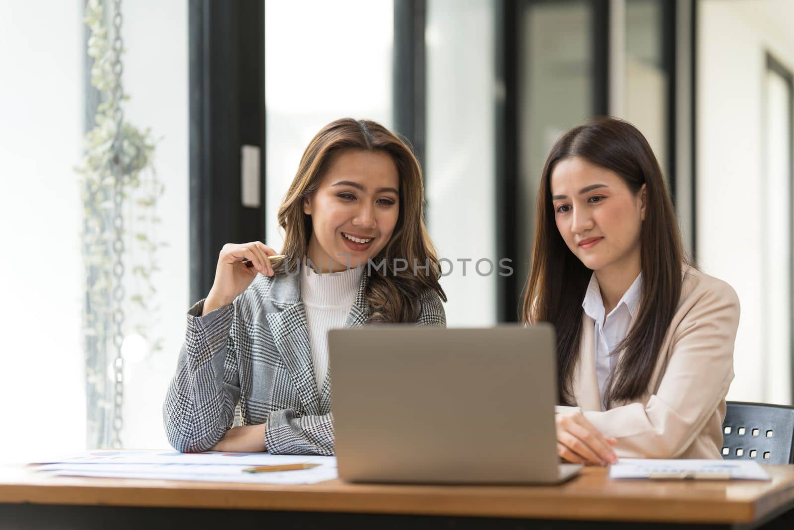 Two young Asian businesswoman discuss financial management planning. new startup project ideas analysis of financial planning and statistics and the investment market at the office by wichayada