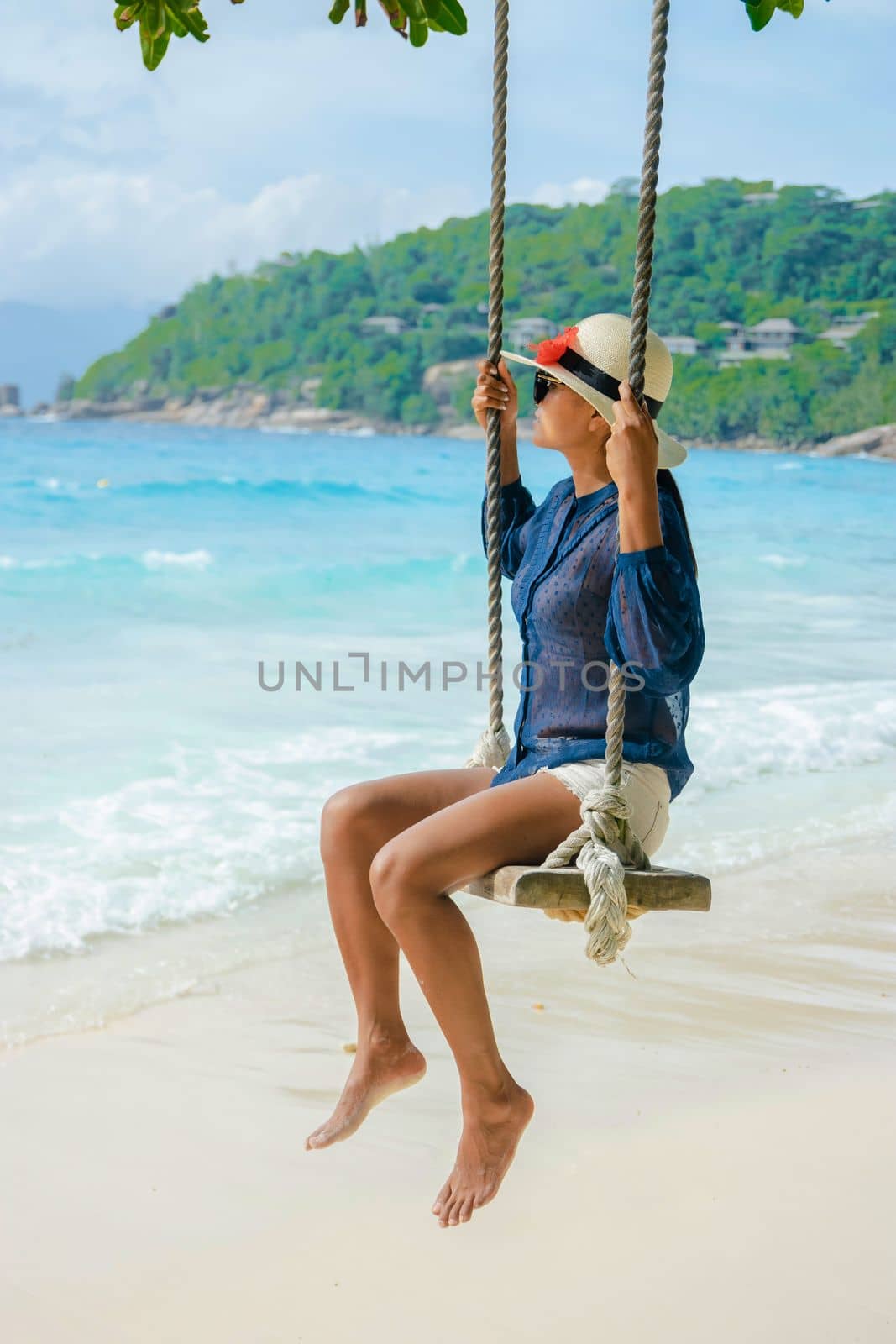 Young women at a swing on a tropical beach in Mahe Tropical Seychelles Islands by fokkebok