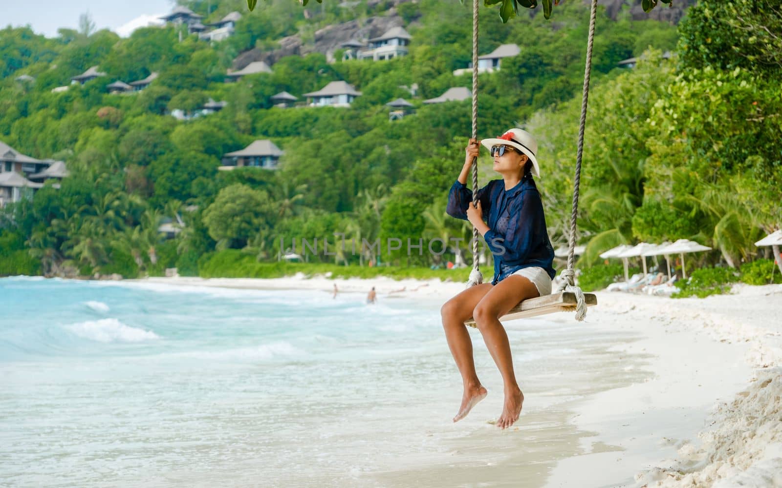 Young women at a swing on a tropical beach in Mahe Tropical Seychelles Islands by fokkebok