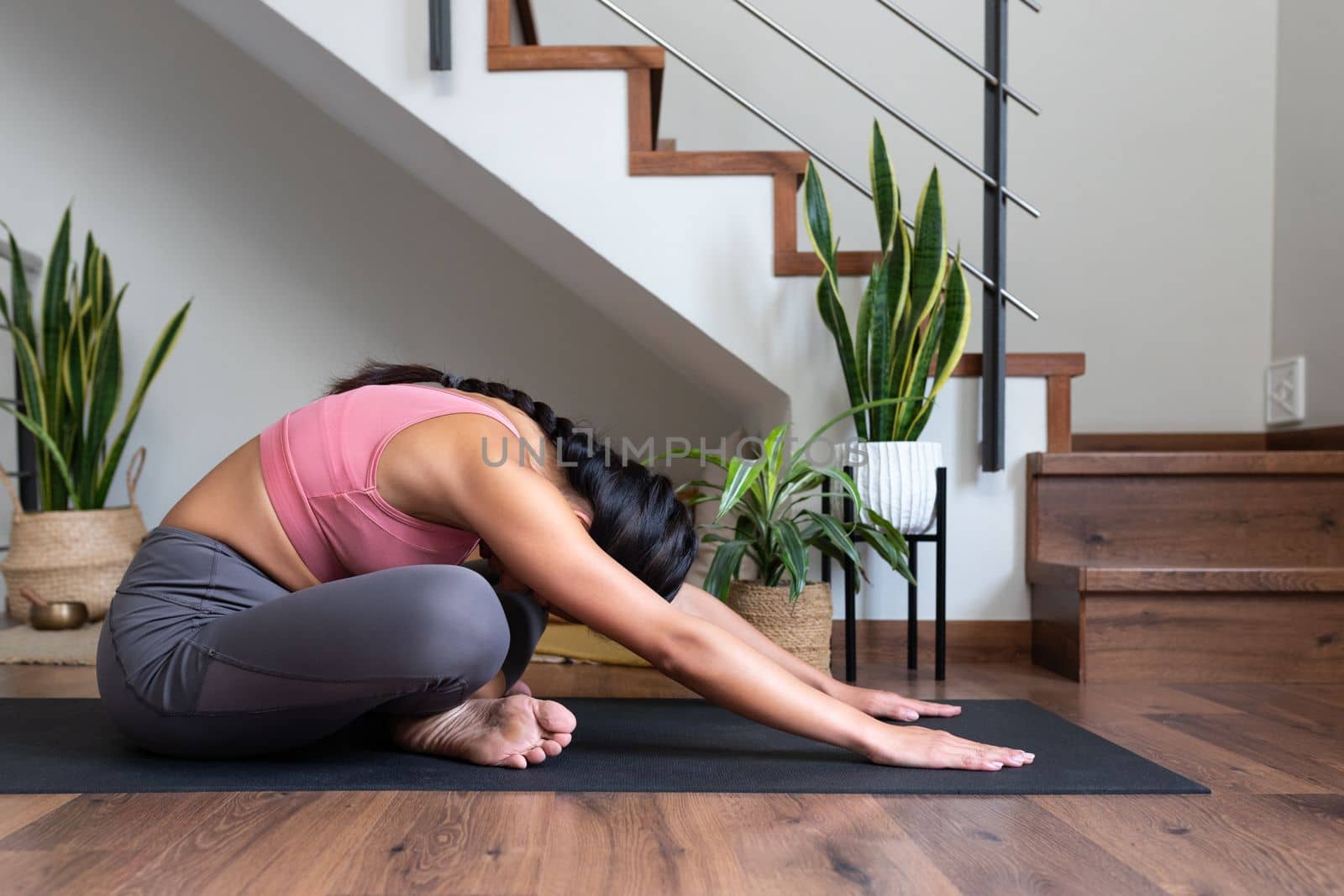 Young woman doing yoga, stretching low back at home. by Hoverstock