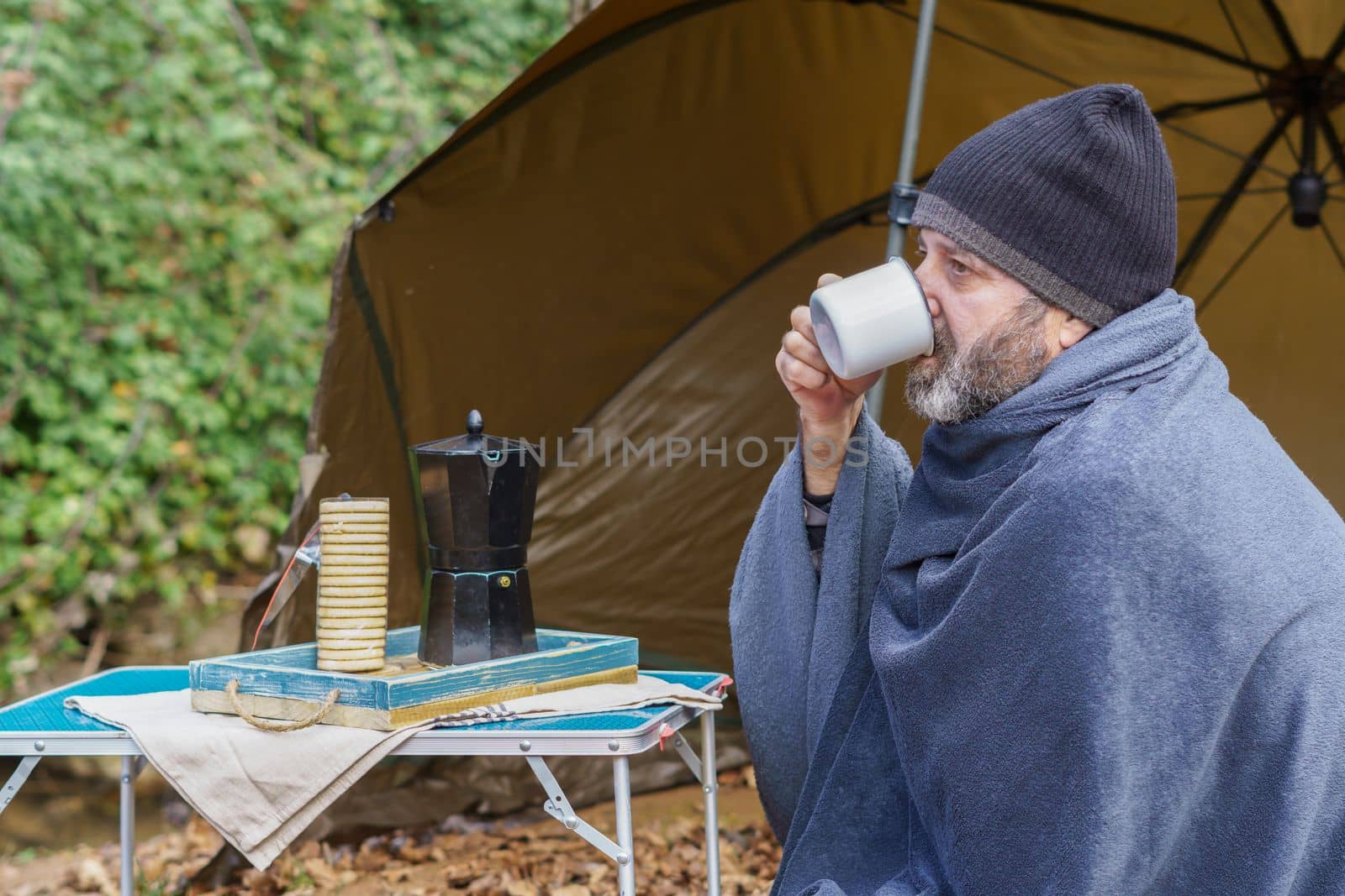 man on a camping trip having a cup of coffee by joseantona