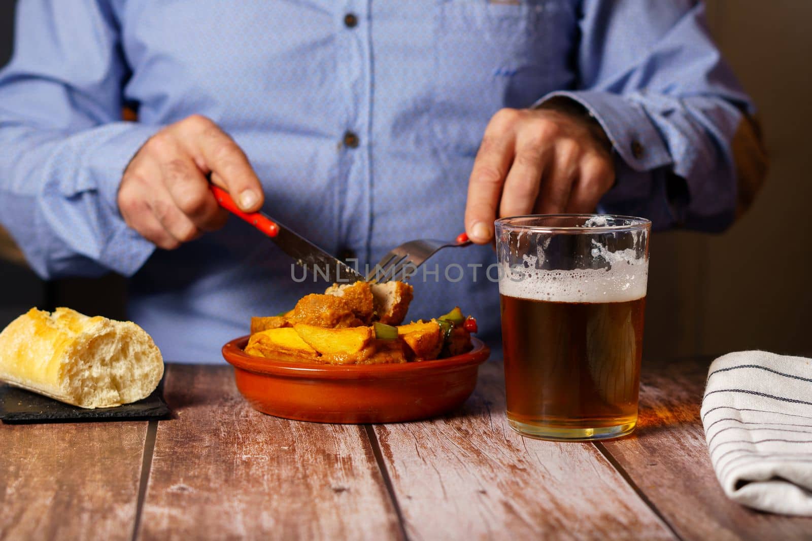 man with beard and blue shirt eating meatballs with spaghetti in a restaurant