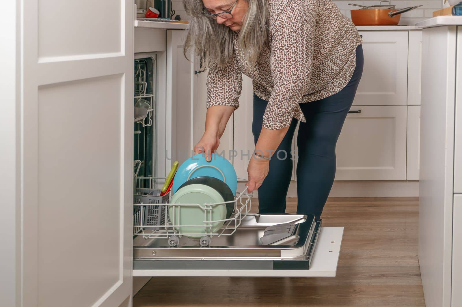woman putting the dishes in the dishwasher by joseantona