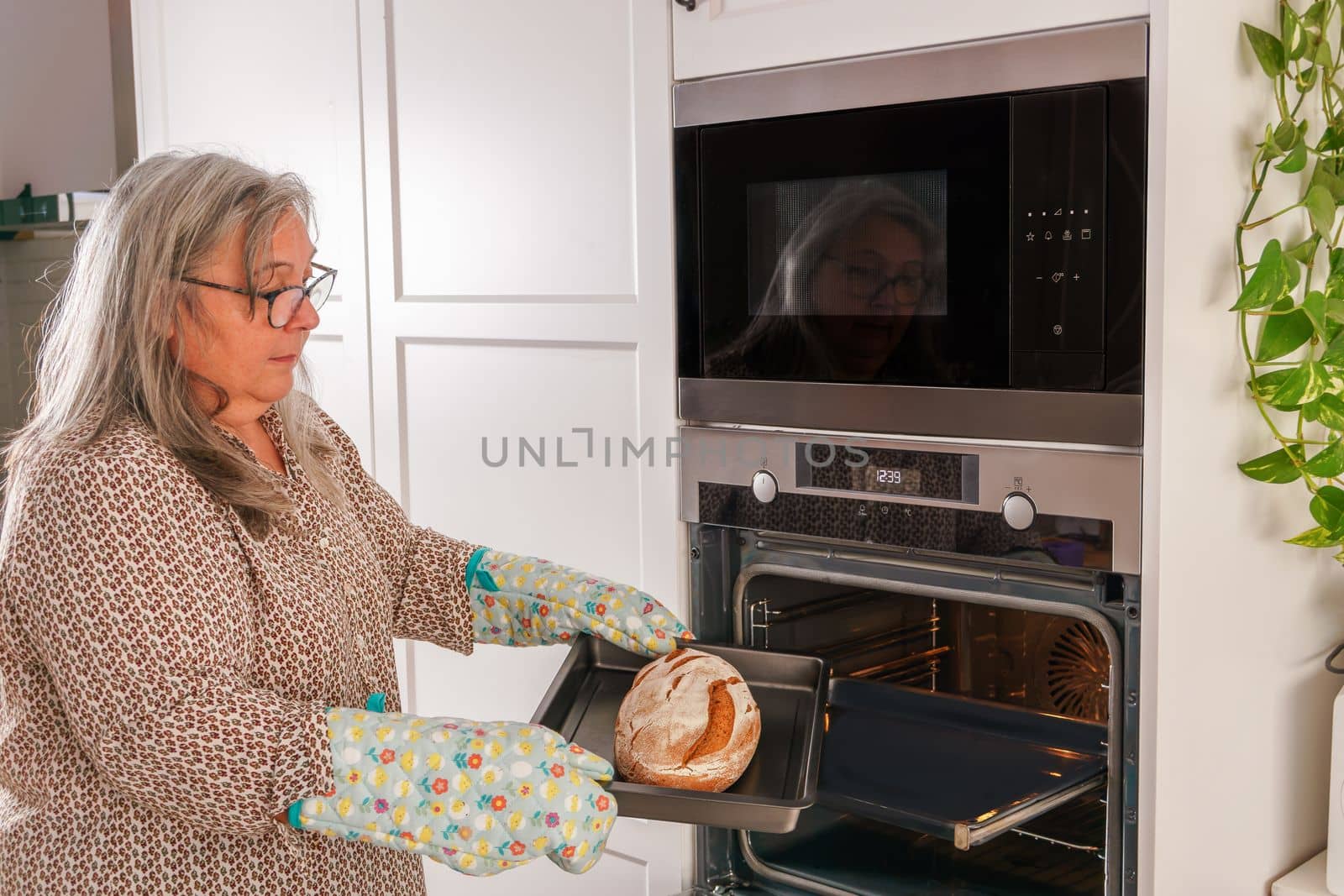 woman putting bread in the oven by joseantona