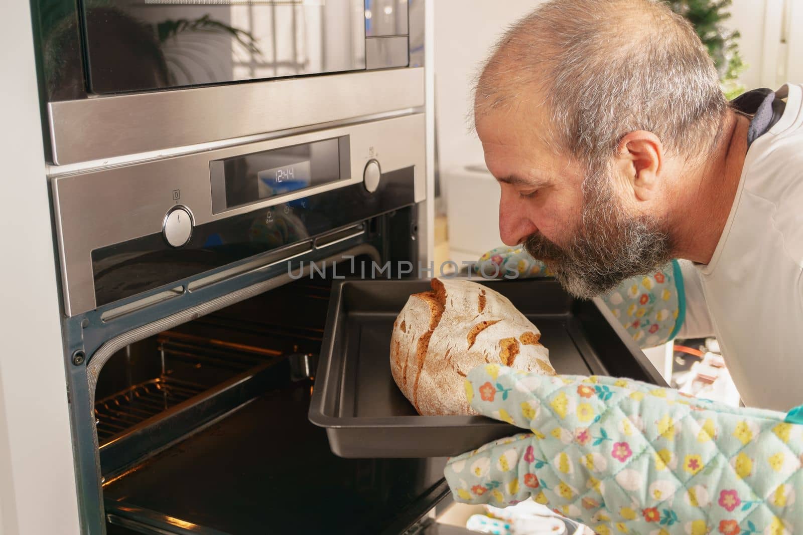 older man with beard putting bread in the oven of his house