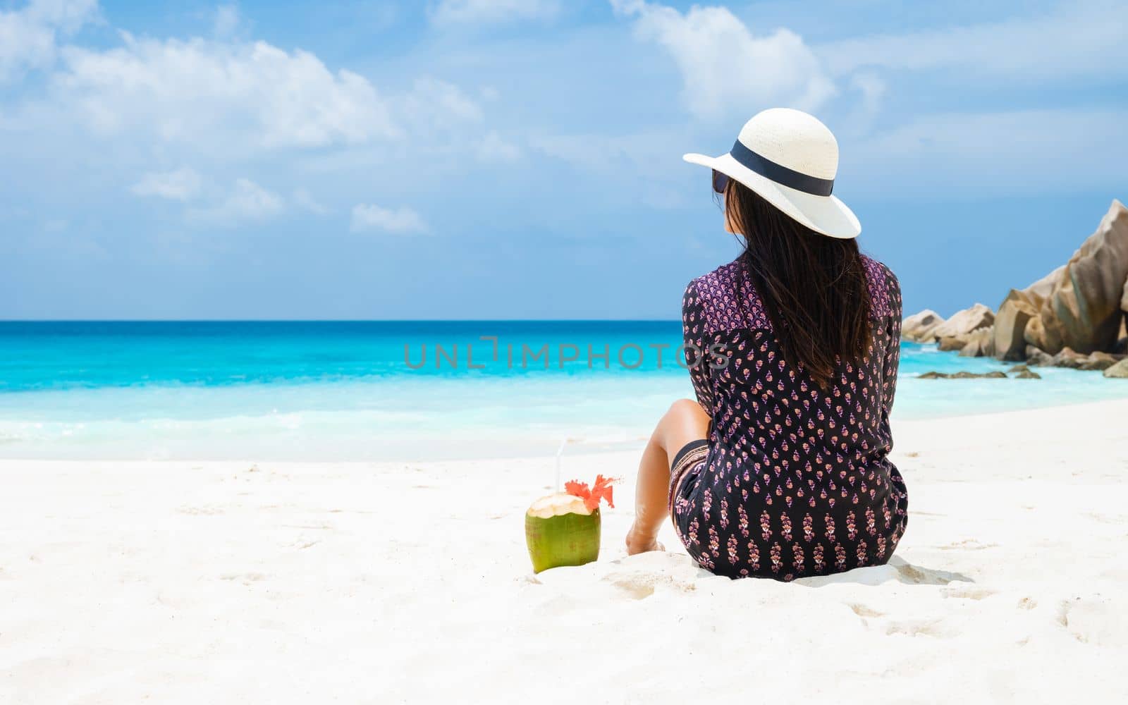 Women with a coconut drink on a tropical beach La Digue Seychelles Islands.