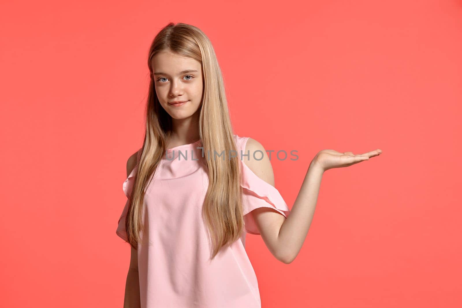 Studio portrait of a fine blonde teenager with a long hair, in a rosy t-shirt, standing against a pink background in various poses. She expresses different emotions posing right in front of the camera, smiling and holding something.