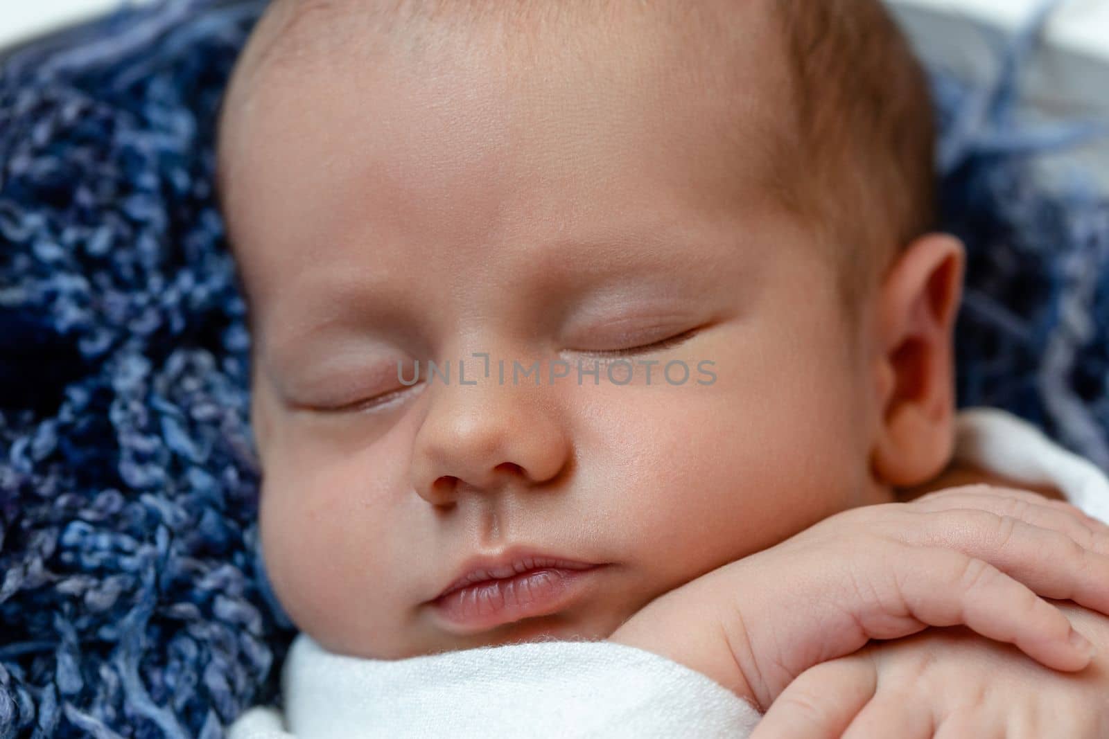 Little baby boy sleeping in a basket on the wooden floor, studio shot. Newborn. 14 days. Close-up
