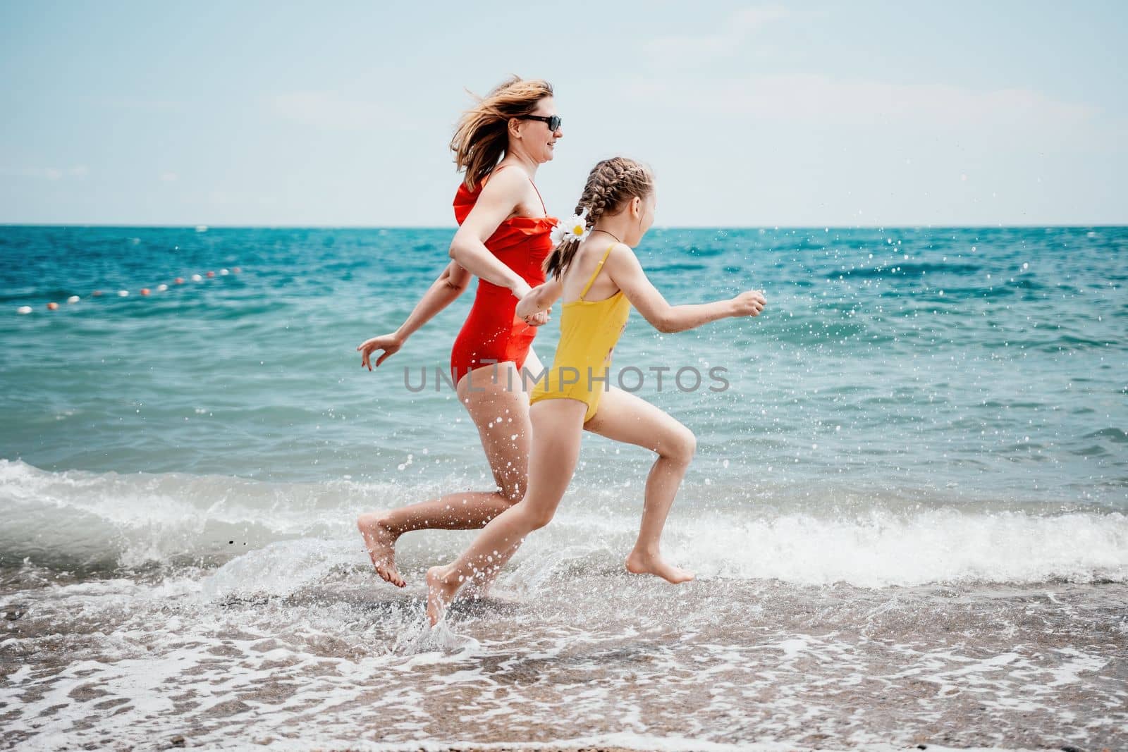 Happy loving family mother and daughter having fun together on the beach. Mum playing with her kid in holiday vacation next to the ocean - Family lifestyle and love concept.