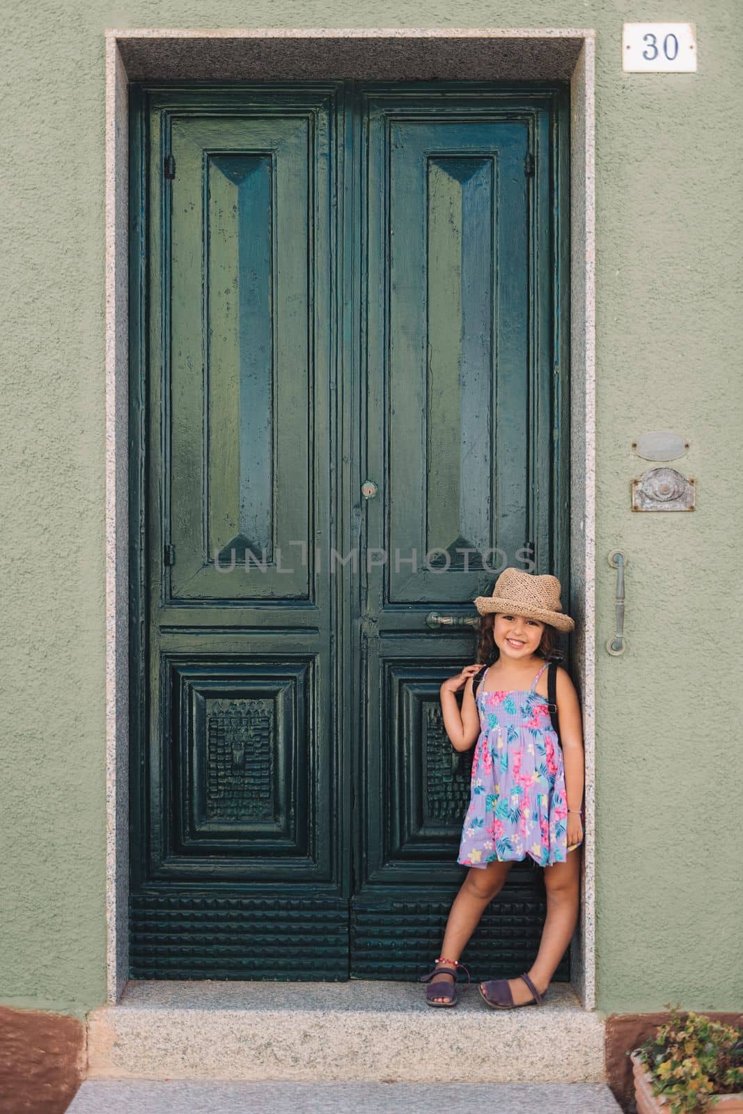 Little girl poses smiling in front of a green door by raulmelldo