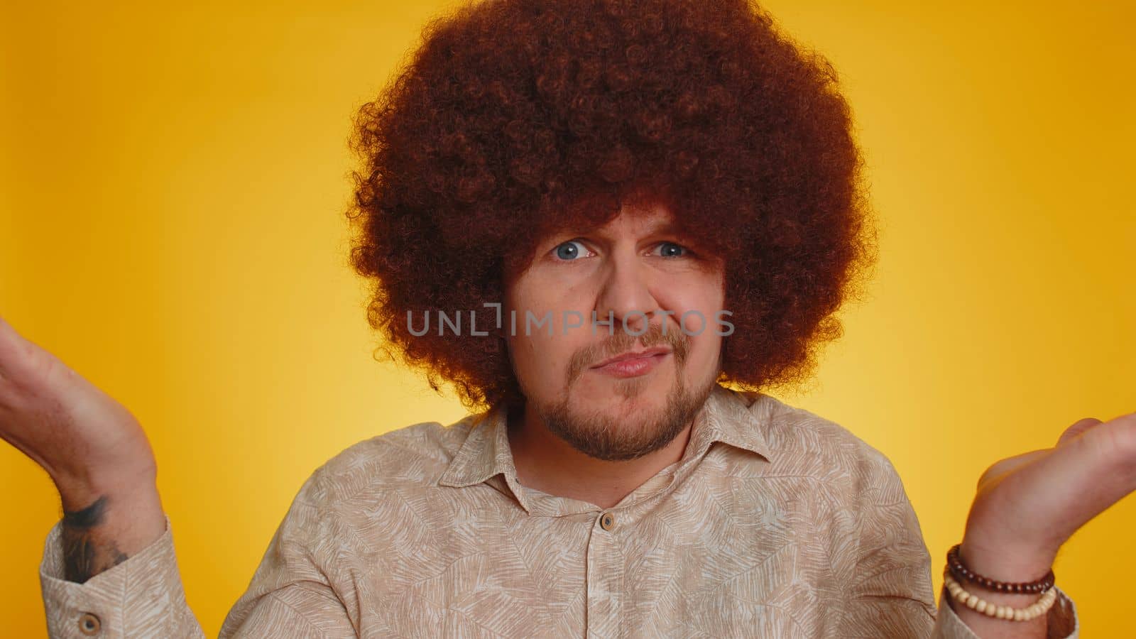 What Why. Sincere irritated man with lush afro hairstyle raising hands in indignant expression asking reason of failure demonstrating disbelief irritation by trouble. Confused guy on yellow background