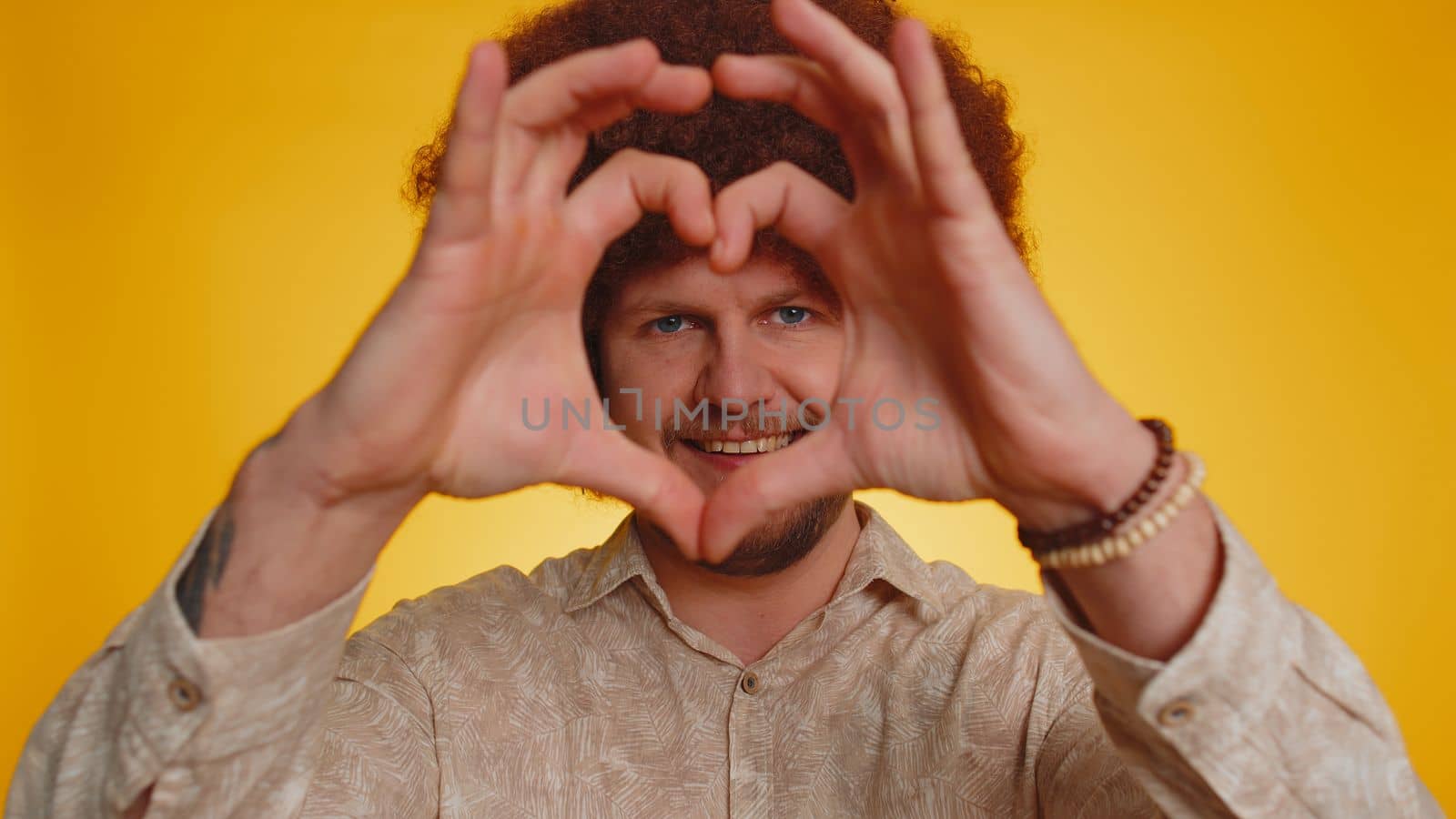 Smiling happy man makes heart gesture demonstrates love sign expresses good feelings and sympathy by efuror
