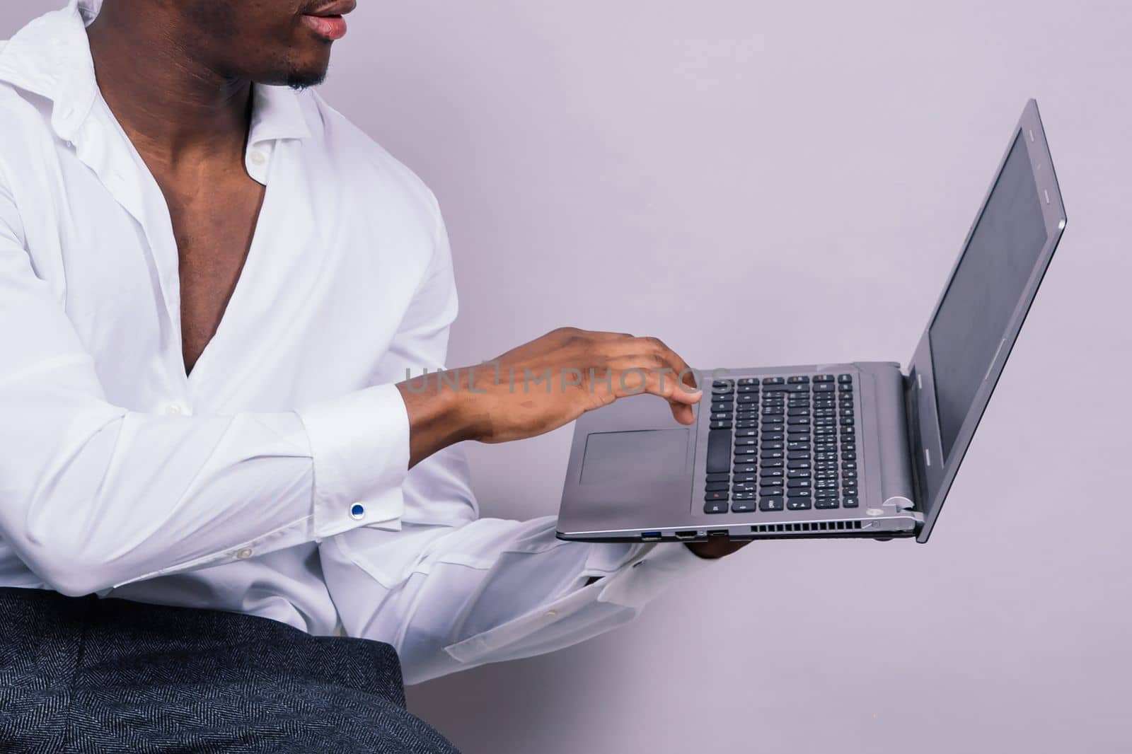 Optimistic african-american male student in casual shirt using laptop pc isolated by Zelenin