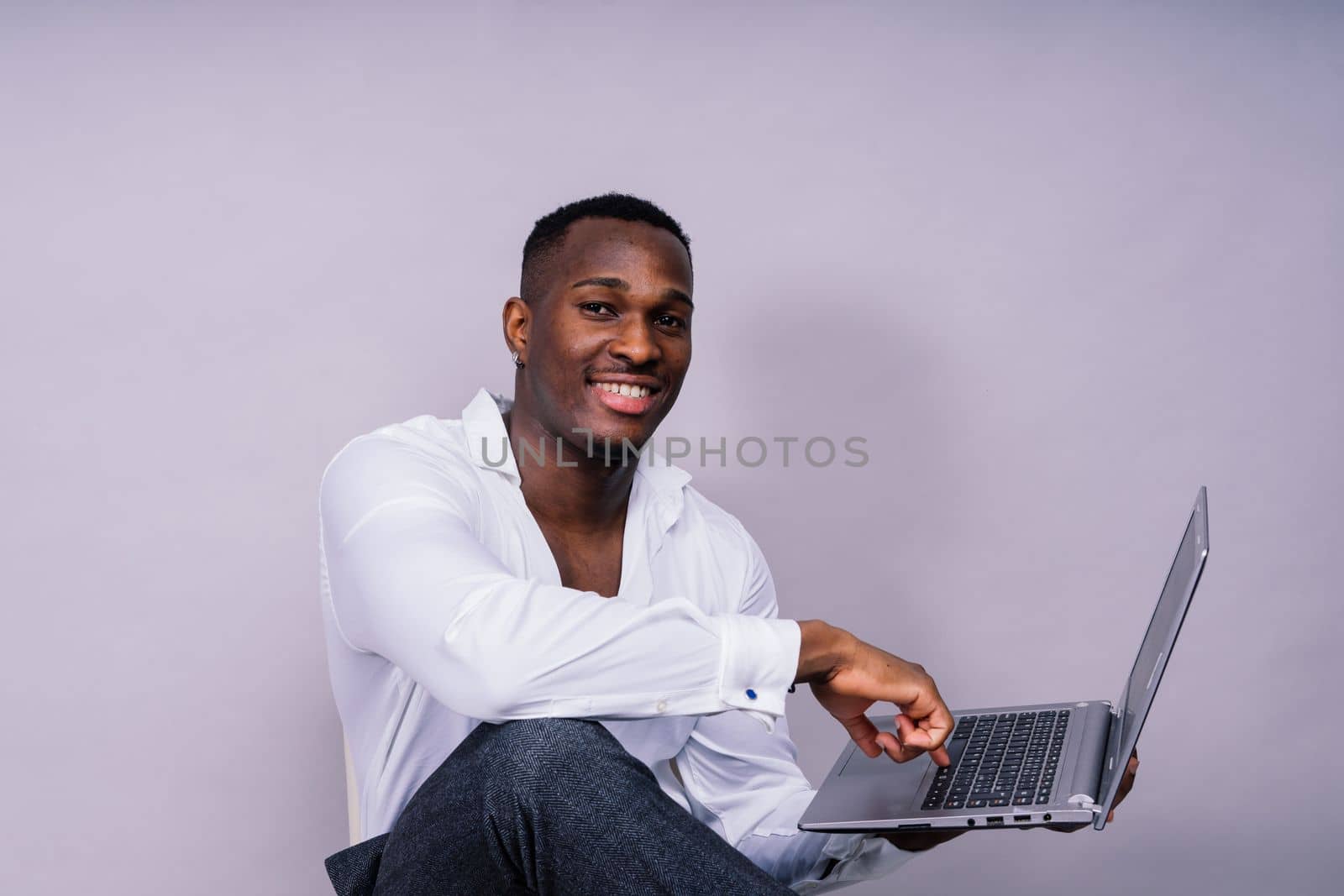 Optimistic african-american male student in a casual shirt using laptop pc isolated