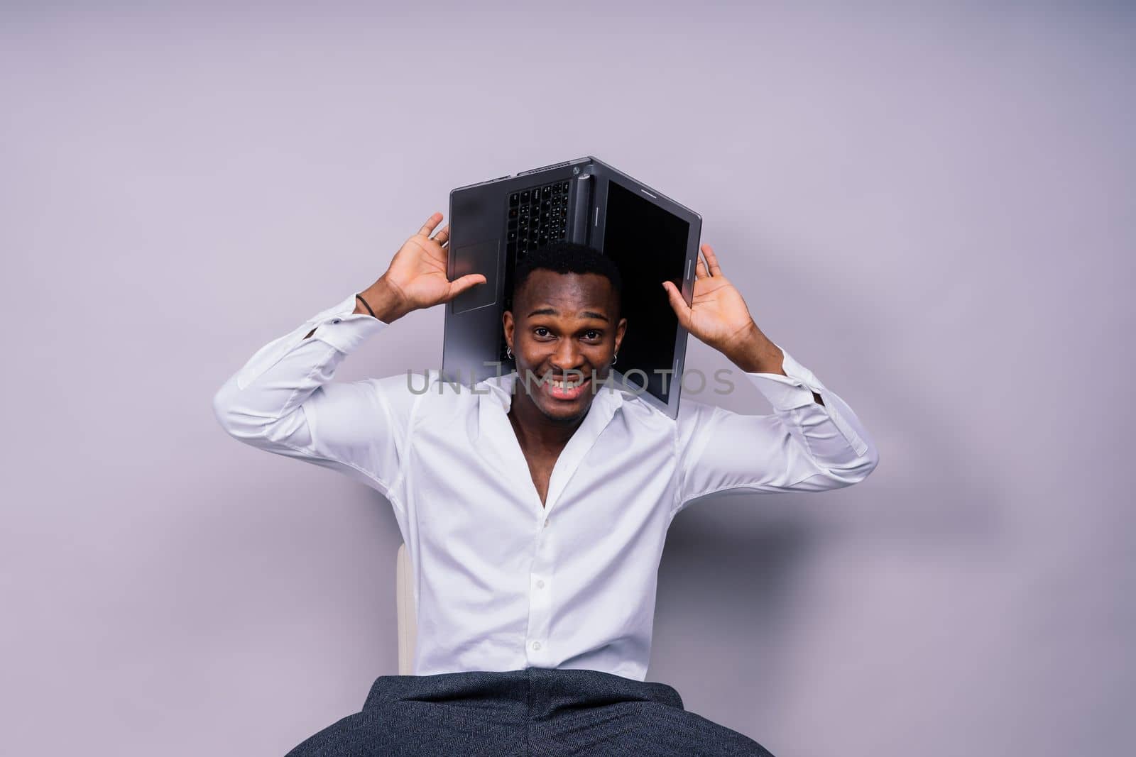 Optimistic african-american male student in a casual shirt using laptop pc isolated