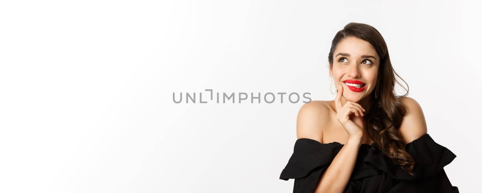 Fashion and beauty concept. Close-up of beautiful dreamy woman with red lips, looking at upper left corner and smiling tempted, having idea, standing over white background.