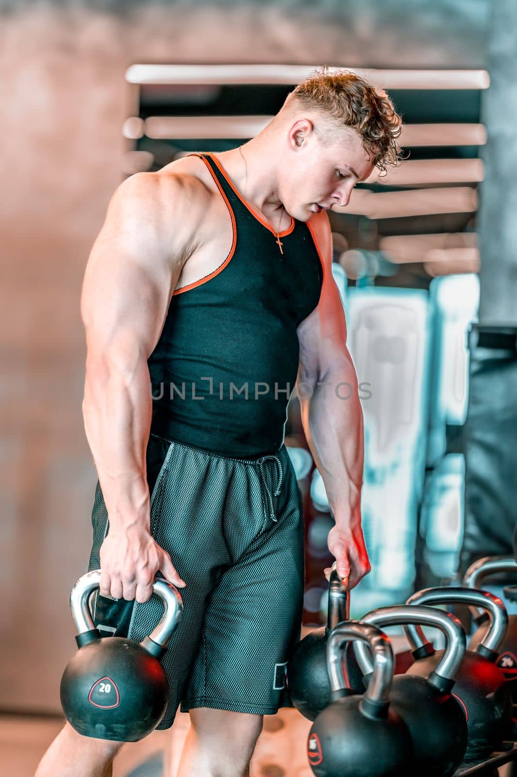 athlete uses kettlebells in rack at gym by Edophoto
