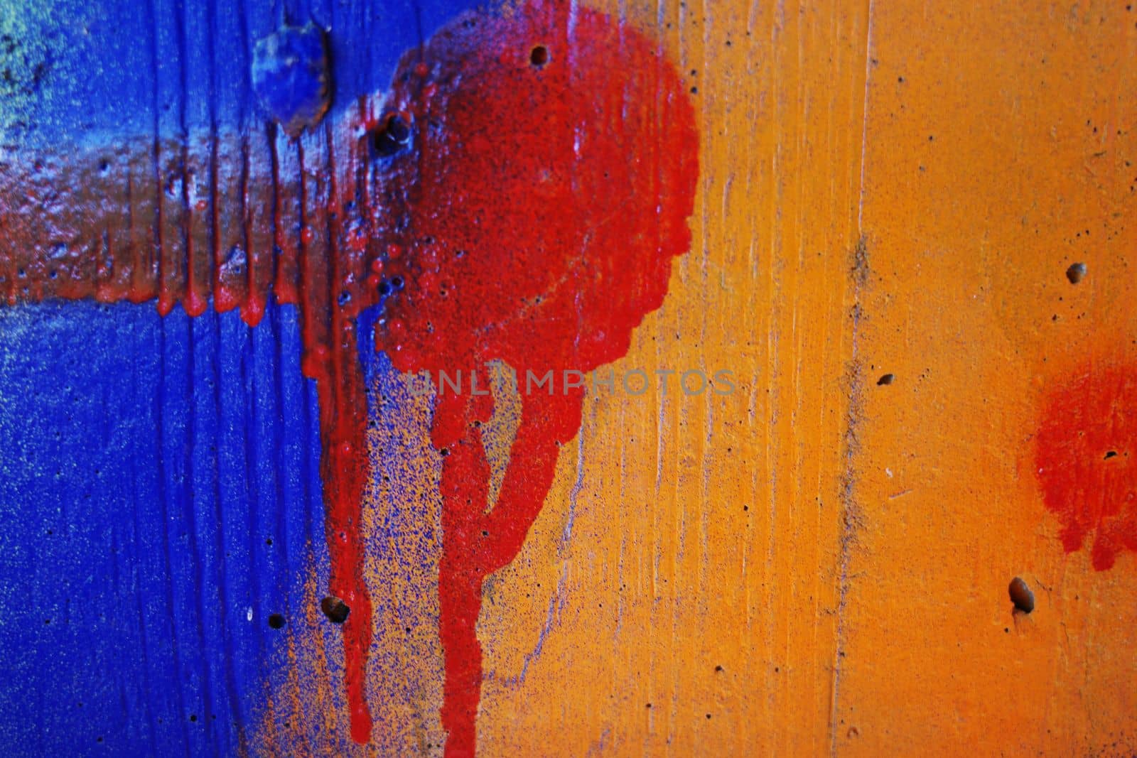 Dripping red paint on a blue and orange concrete wall. Meant as a colorful background