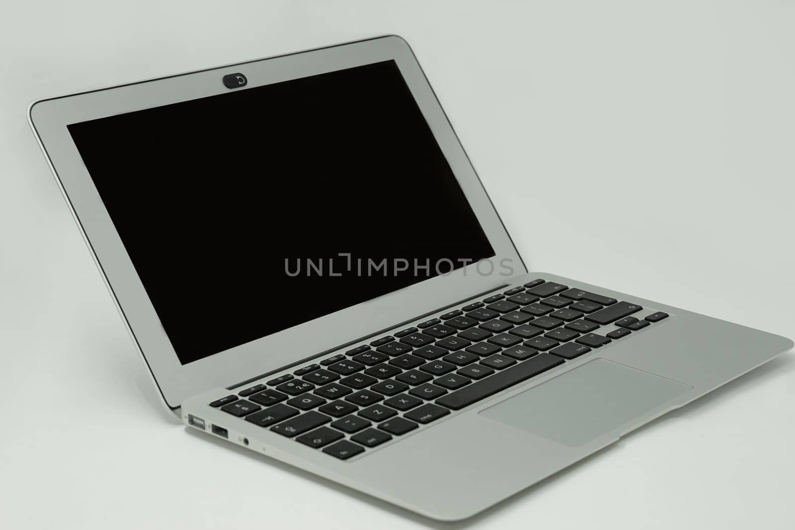 A small silver ultra light laptop with black screen and black keys on white background