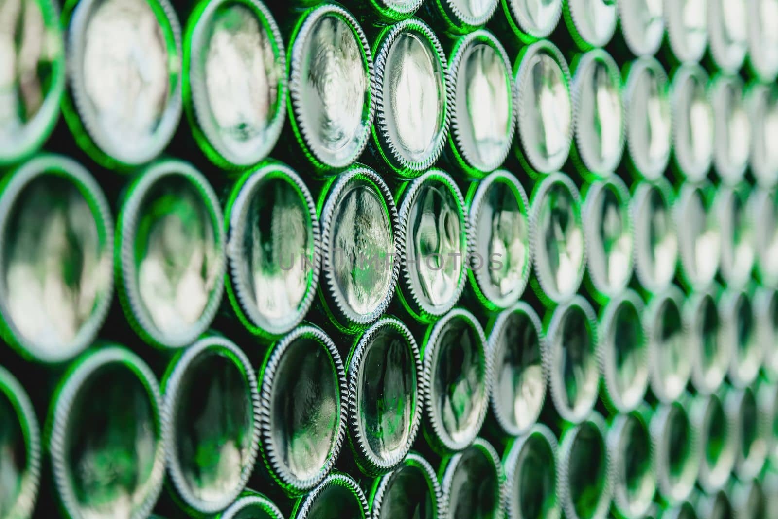 Glass bottles green. Green glass bottles of beer. Wall formed by green bottles. Green bottles background. Empty Glass Bottle with Lighting.