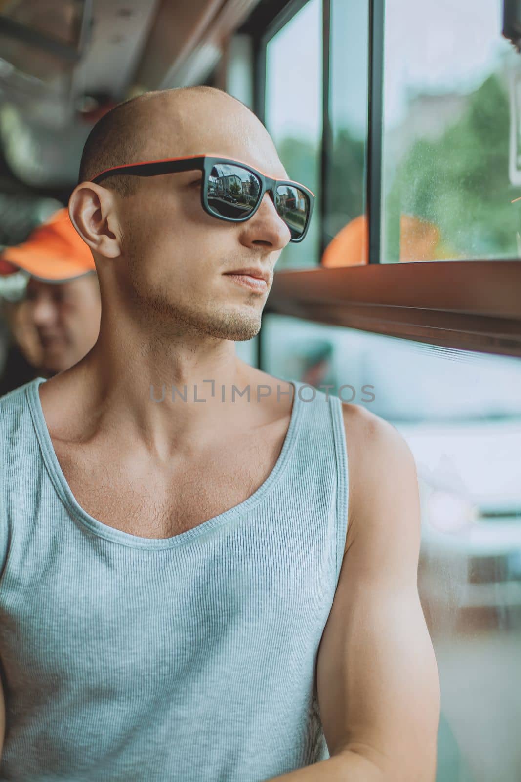 Young mansmartphone travelling by bus in city. A young man wearing a T-shirt and sunglasses uses a mobile phone on public transport. A man on a bus with a mobile phone by ViShark