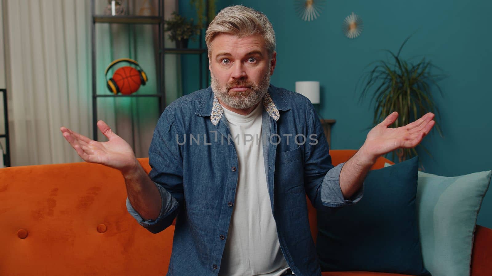 I dont know what to say. Confused middle-aged man feeling embarrassed about ambiguous question, having doubts, no idea, being clueless, uncertain at home. Mature senior gray-haired guy at night room