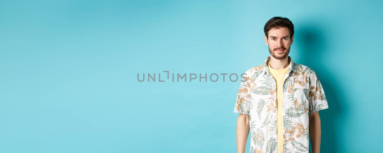 Happy handsome guy smiling, wearing hawaiian shirt on vacation. Concept of summer holiday.