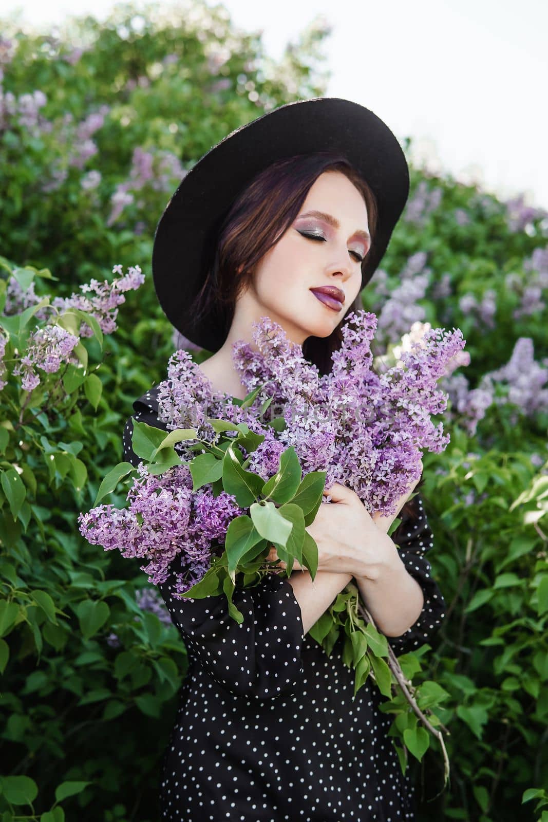 A fashionable girl with dark hair, a spring portrait in lilac tones in summer. Bright professional makeup