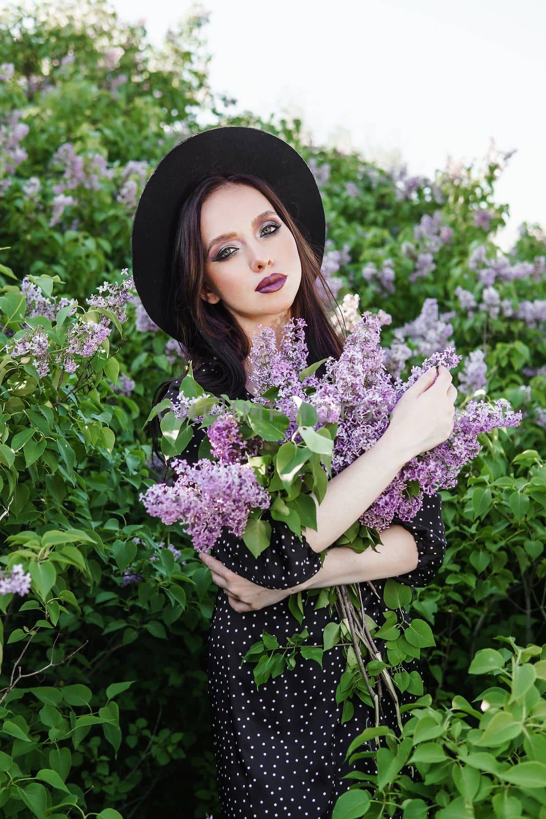 A fashionable girl with dark hair, a spring portrait in lilac tones in summer. Bright professional makeup