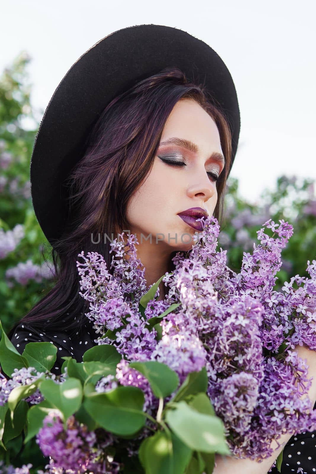 A fashionable girl with dark hair, a spring portrait in lilac tones in summer. Bright professional makeup