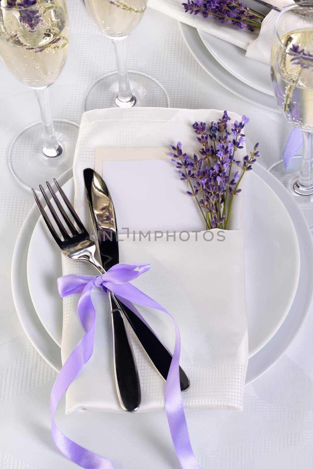 Lavender mood. Dining table in Provence style, with Lavender Champagne, folded napkin with cutlery, decorated with fresh lavender. Detail of the wedding dinner. Wedding theme ideas.