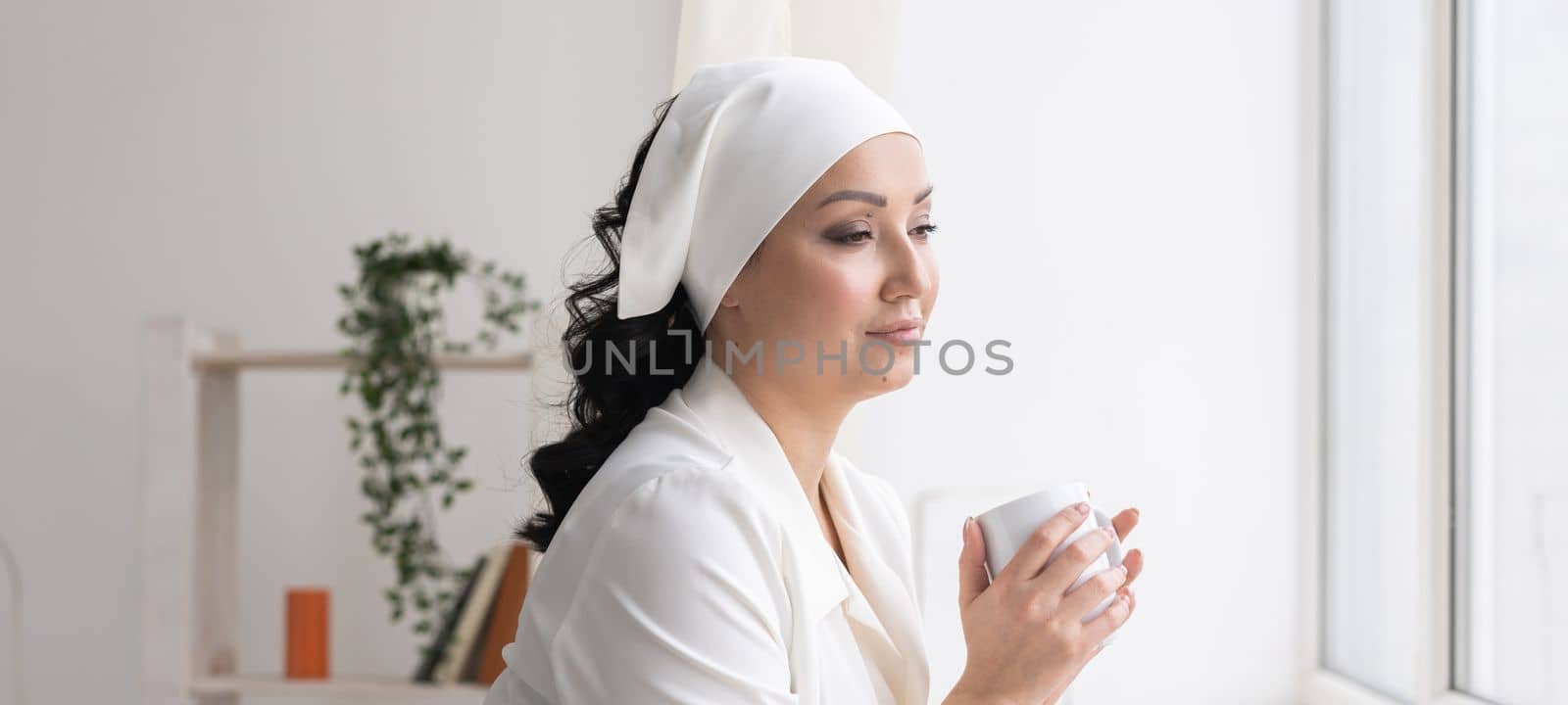 Beautician or nurse drinking coffee during a break on background beauty office. Portrait of professional beautician - copy space and empty place for advertising by Satura86