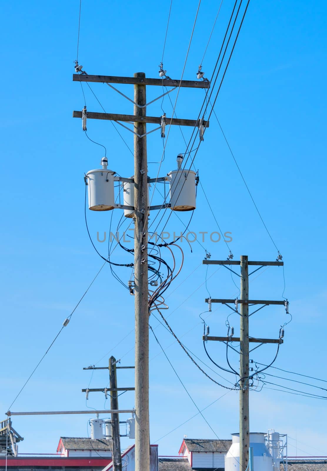 Electric posts and power transmission line, wooden electricty pole with mounted transformators on blue sky background