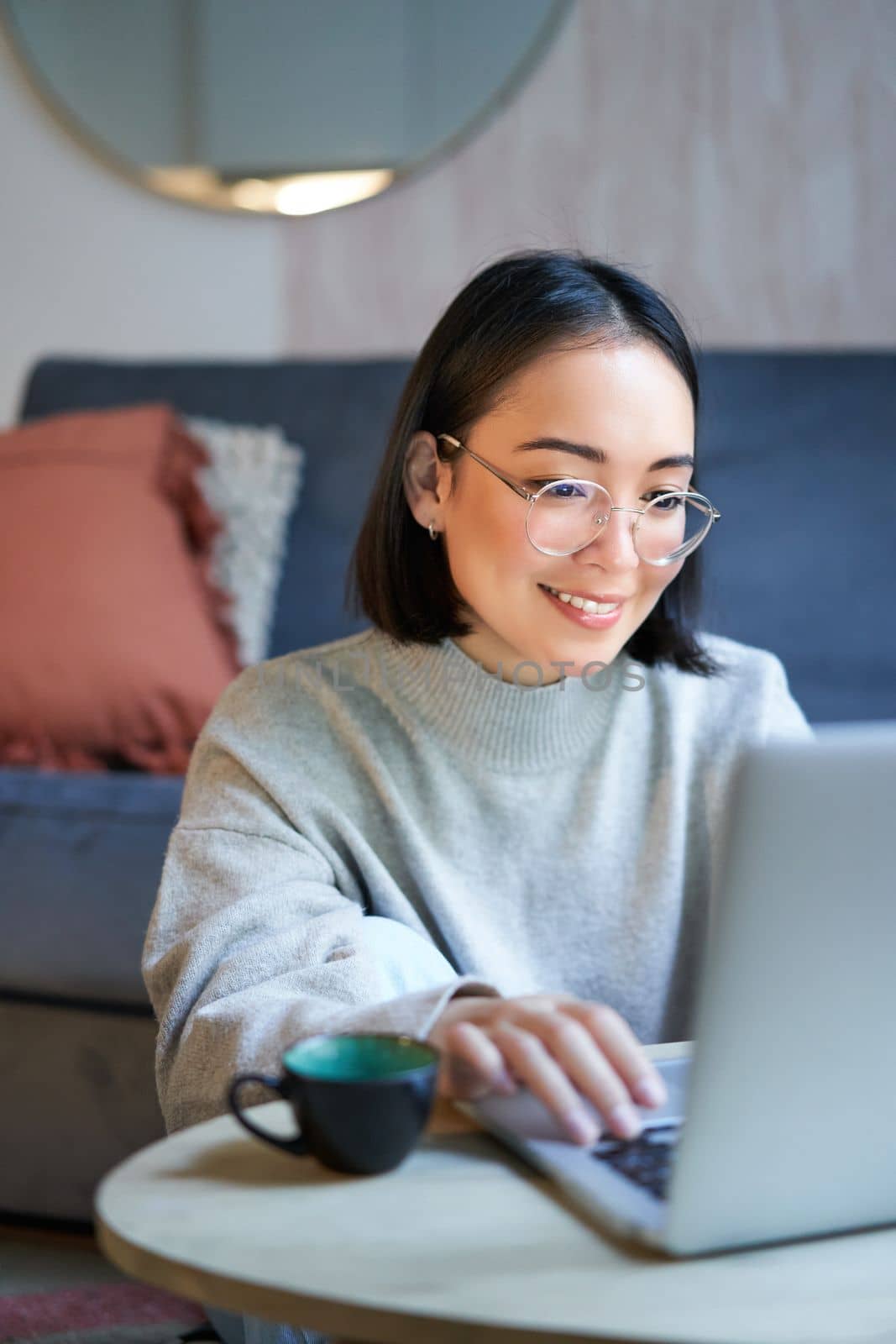 Young asian girl, freelancer professional sitting in living room and working with computer, studying at home using computer.