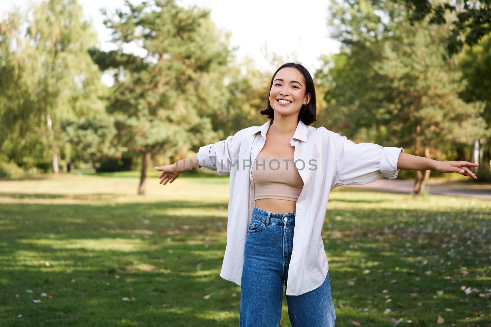 Happy asian girl dancing in park, feeling freedom and joy, walking outdoors on sunny day by Benzoix