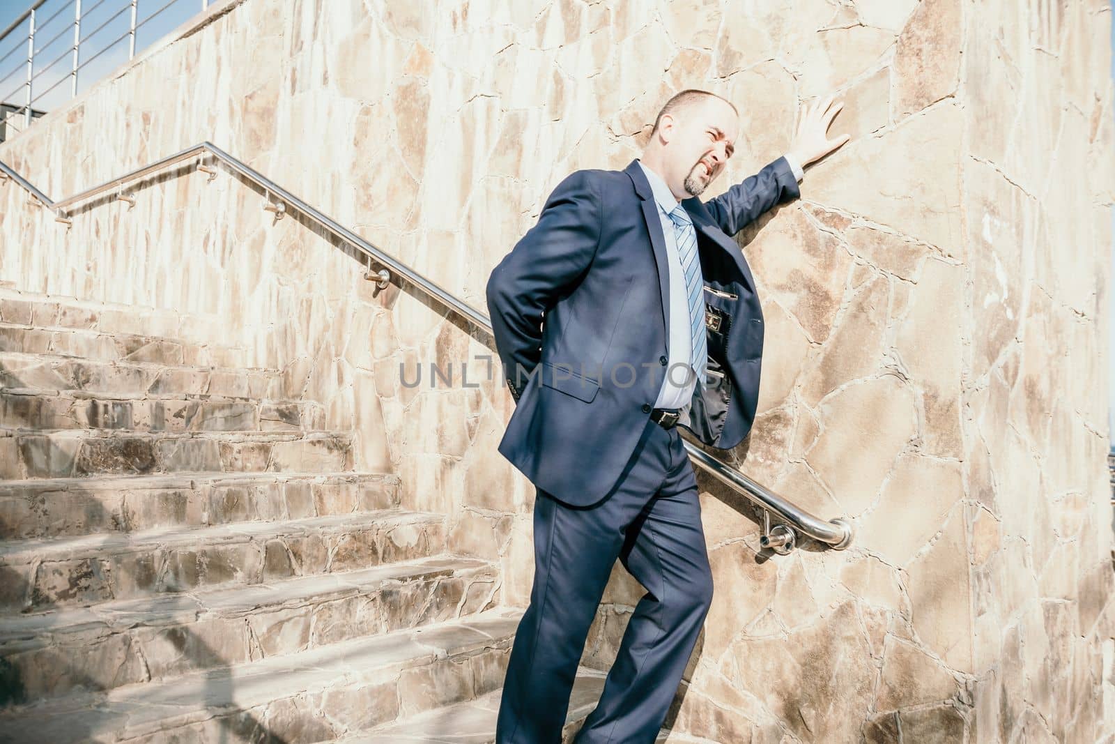 Portrait of a senior professional man in a suit with various problems. A middle-aged businessman with a briefcase descends the stairs.