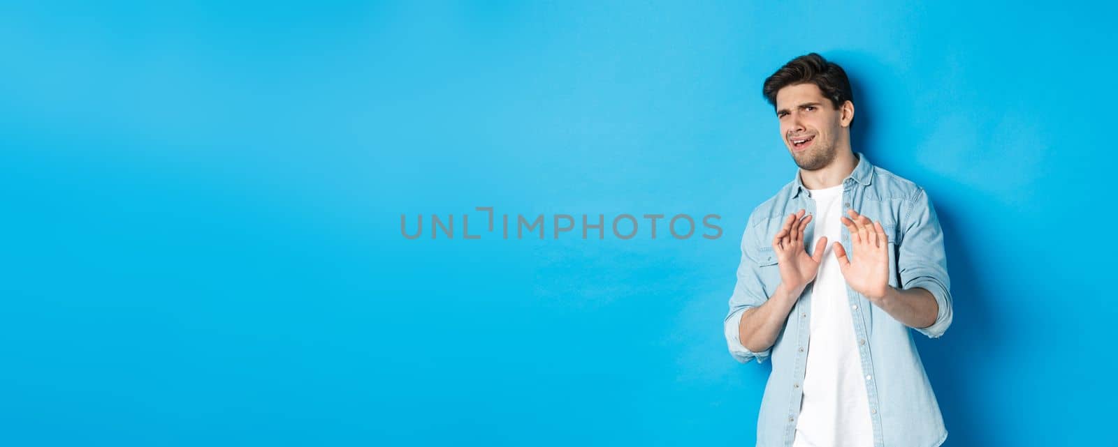 Displeased man refusing, saying no and cringe from something disgusting, standing over blue background by Benzoix