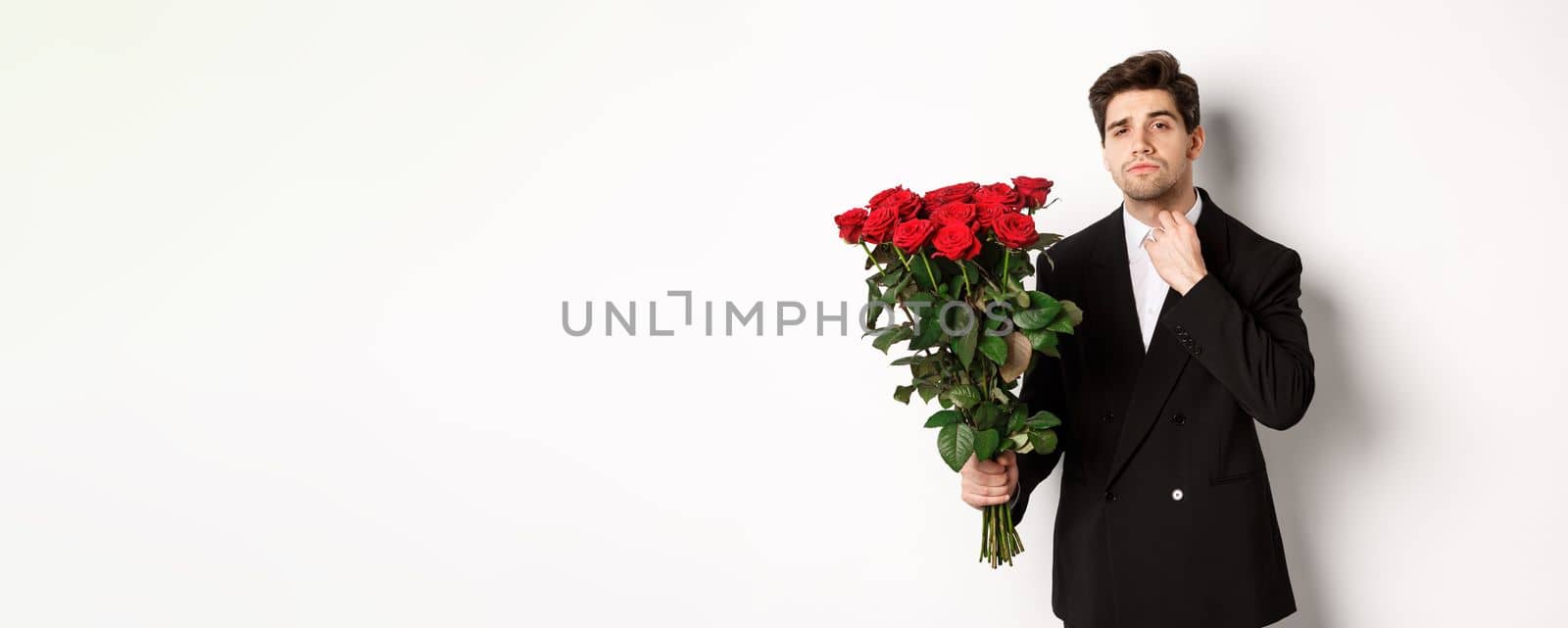 Image of elegant and sassy man in black suit, looking confident and holding bouquet of red roses, going on a romantic date, standing against white background by Benzoix