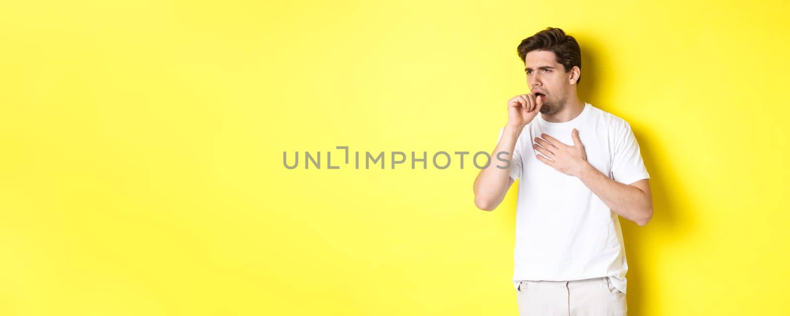 Image of man with covid-19 or flu symptoms, coughing and feeling sick, standing over yellow background by Benzoix