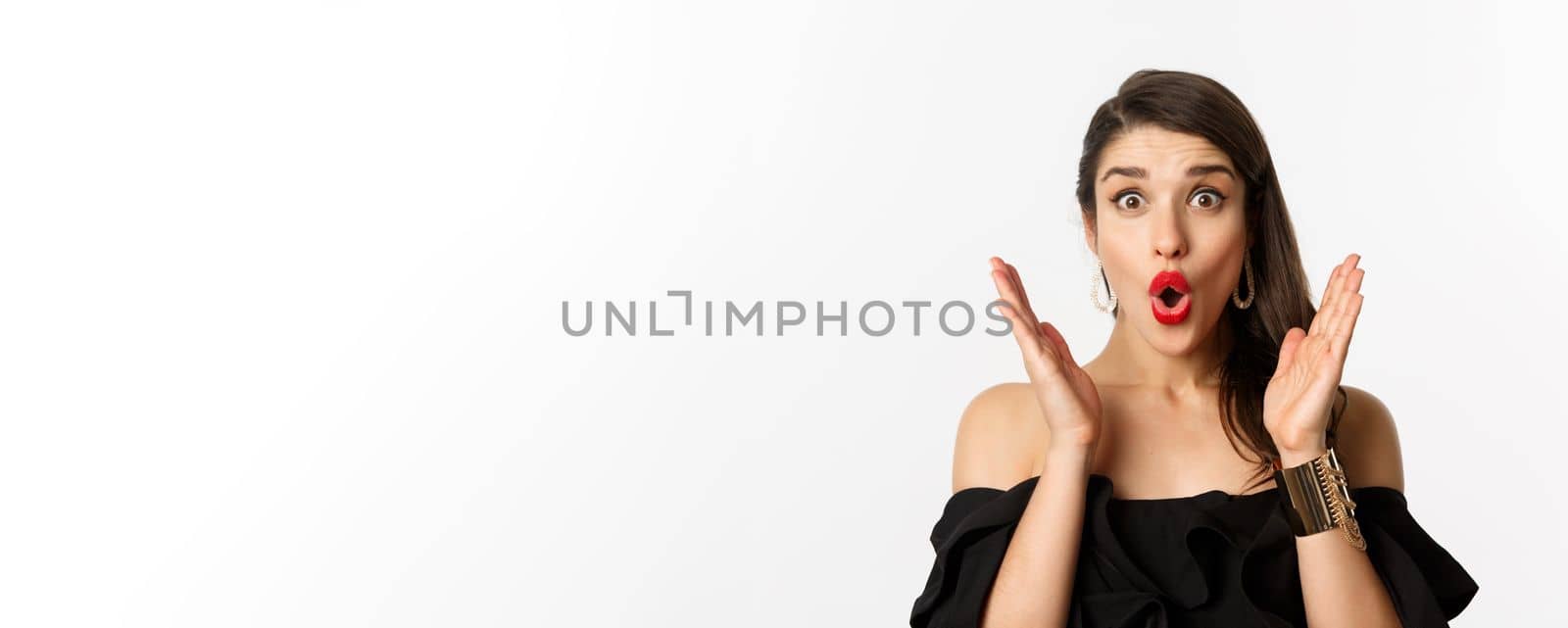 Fashion and beauty concept. Close-up of excited woman with makeup and red lipstick on, looking surprised and glad, standing over white background.