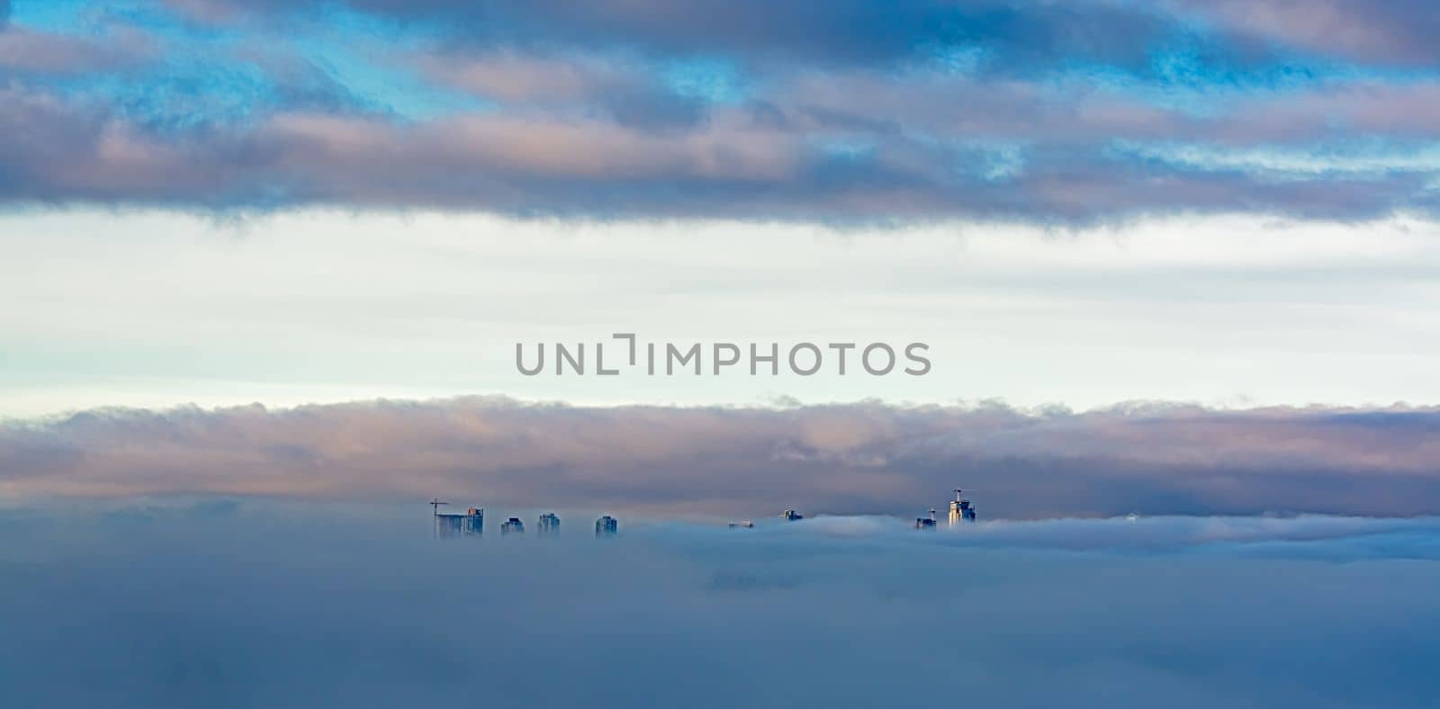 Sunrise view at Metrotown towers covered with the fog on cloudy sky background by Imagenet