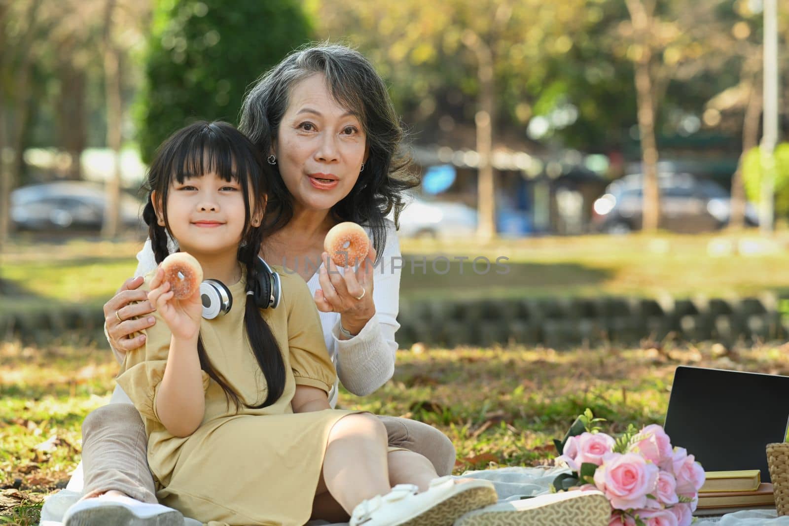 Cute little grandchild and mature grandma having picnic at summer park. Family, leisure and people concept by prathanchorruangsak