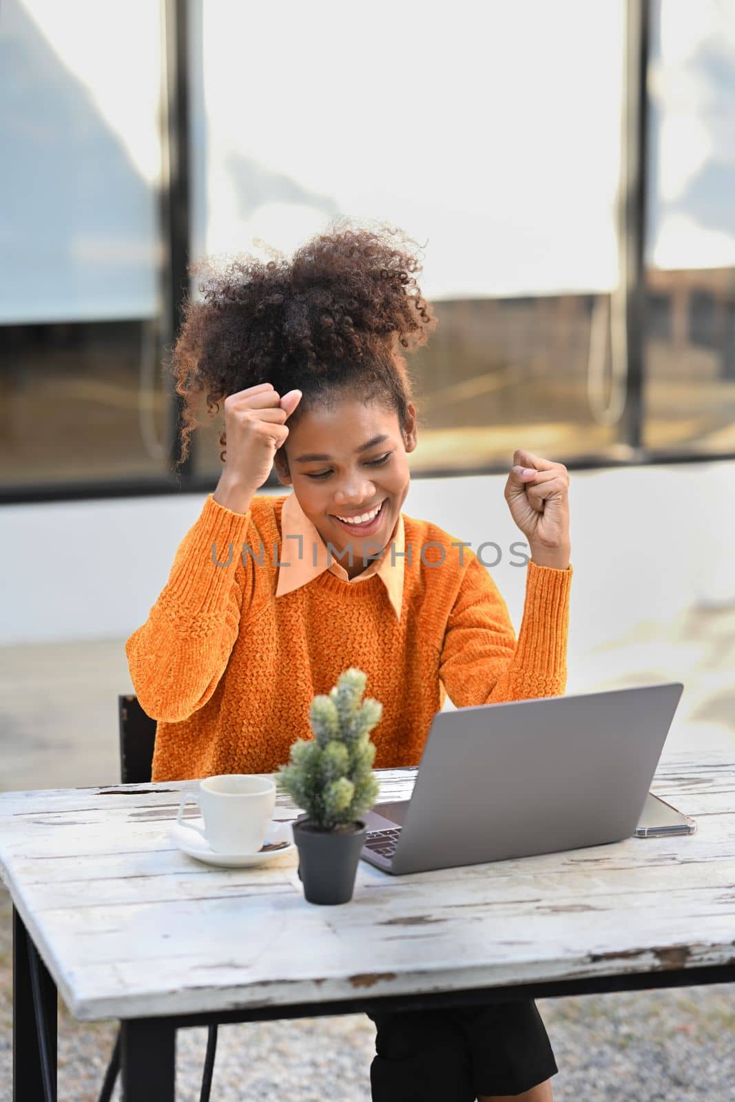 Shot of overjoyed African American woman getting mail, read good news on laptop computer by prathanchorruangsak