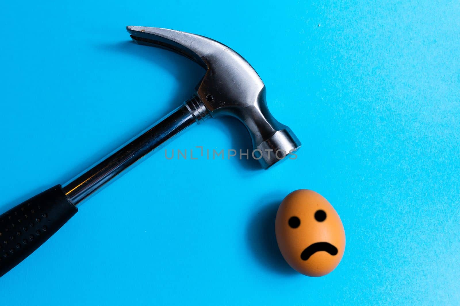 Hammer is hitting on an egg with blue background. minimal idea creative concept. by Zelenin