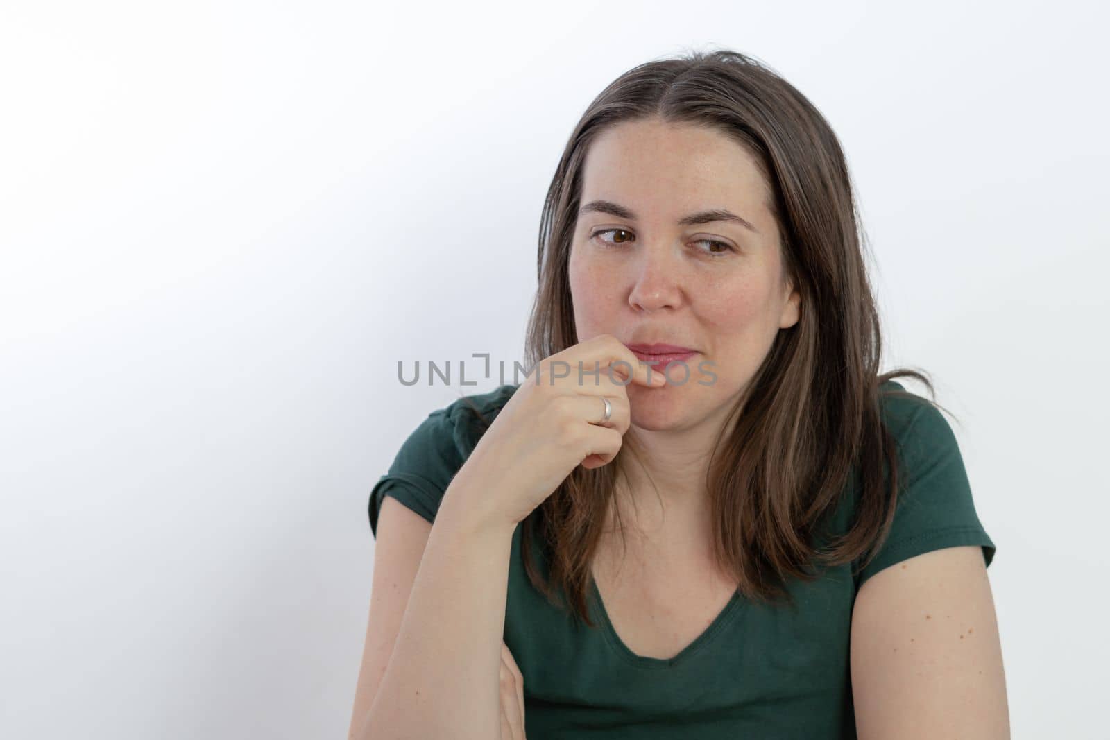 pensive woman looking at the ground with her finger in her mouth by joseantona