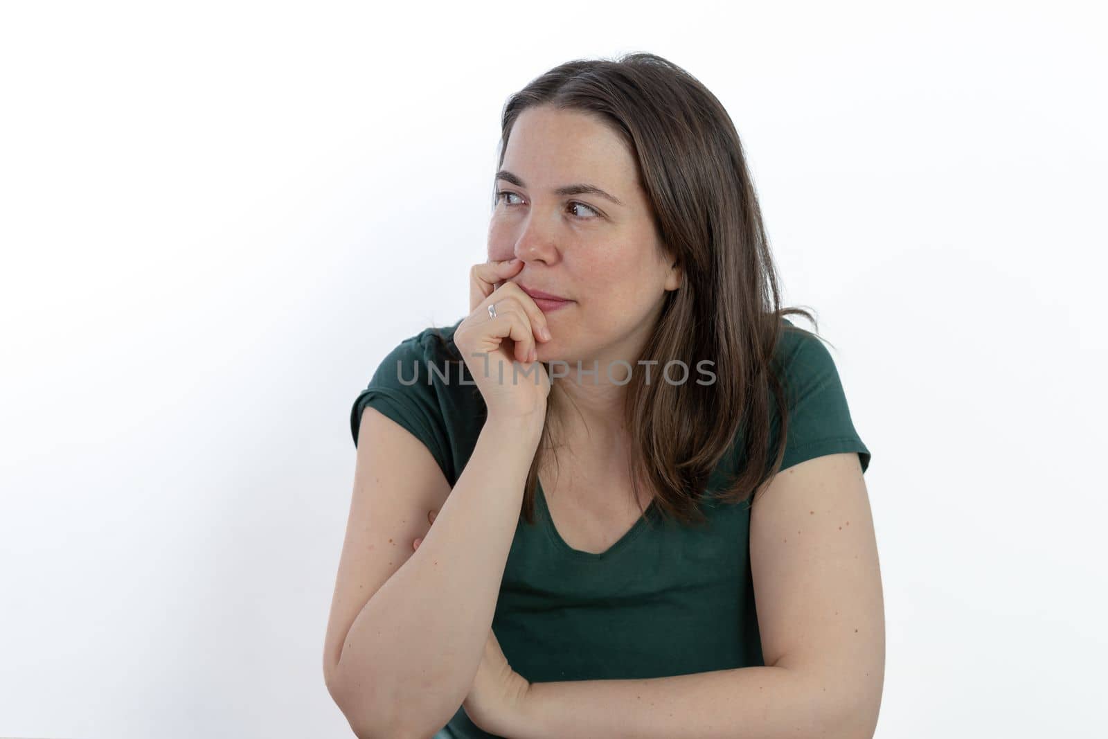 pensive young brunette woman gazing at the sky with her hand on her face white background