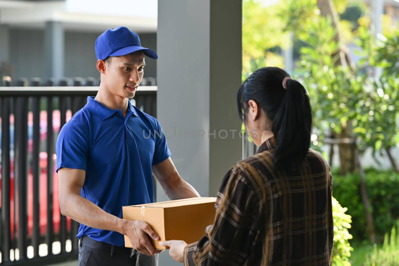 Delivery man giving postal package to customer at doorway. Delivery service, post and shipping concept.